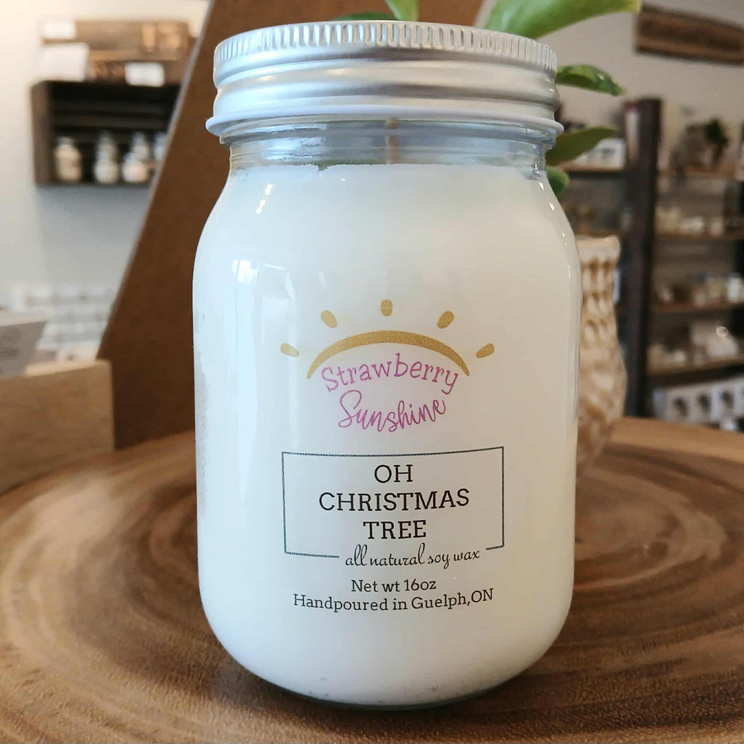 Candle jar labeled 'Strawberry Sunshine' on a wooden surface