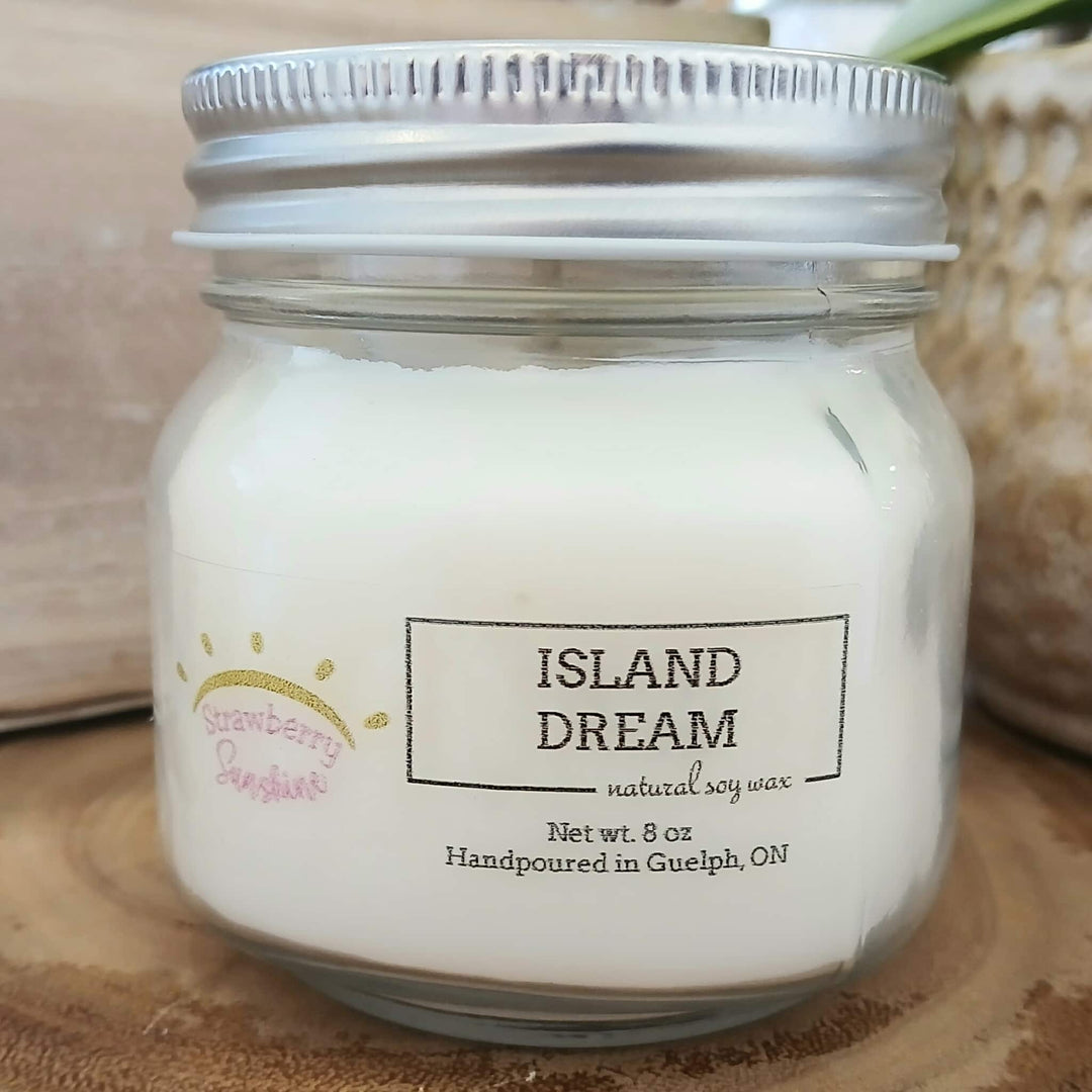 Jar of 'Island Dream' candle with a label on a wooden surface