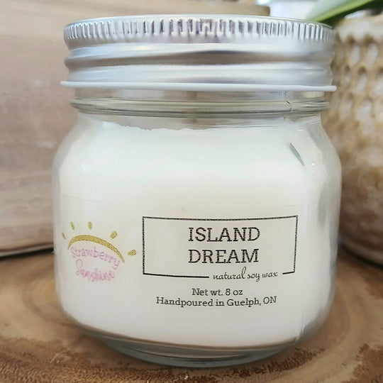 Jar of 'Island Dream' candle with a label on a wooden surface