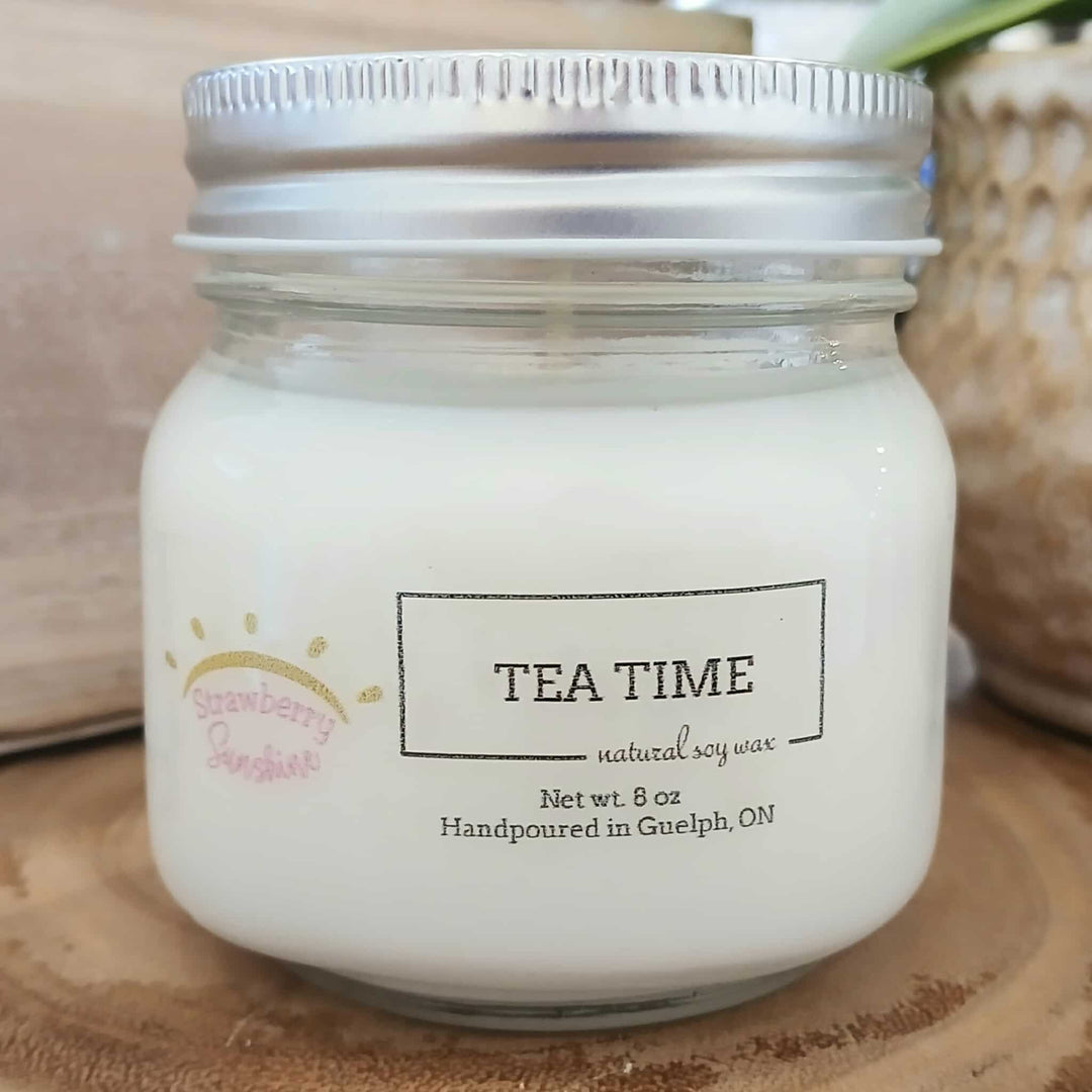 Jar of candle labeled 'Tea Time' on a wooden surface